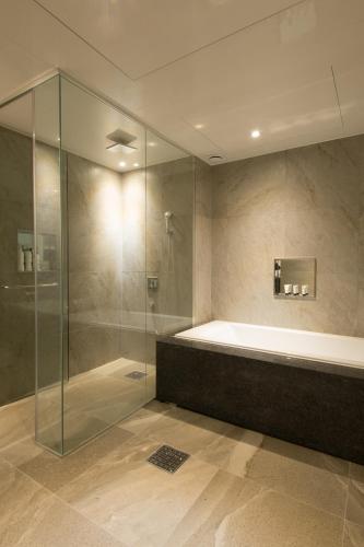 a bathroom with a tub and a glass shower at The Empress Hotel in Daejeon