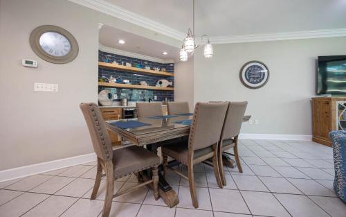 a dining room with a table and chairs and a clock at Phoenix on the Bay 1328 in Orange Beach