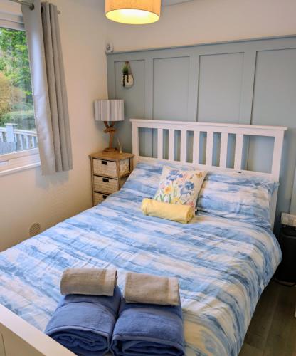a bedroom with a bed with a blue comforter at 147 Snowdon Drive, Glan Gwna Holiday Park in Caernarfon