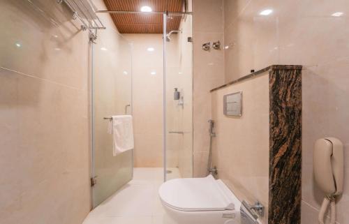 a bathroom with a toilet and a glass shower at Hotel Magenta-City Center Bani Park Jaipur in Jaipur