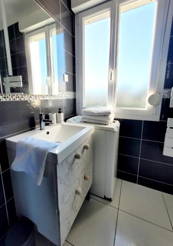a bathroom with a white sink and a window at Duplex les pieds dans l'eau in Grandcamp-Maisy