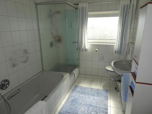 a white bathroom with a tub and a sink at Haus Panorama in Massenbachhausen
