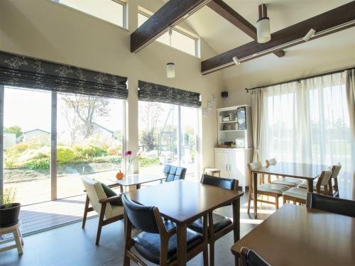 a dining room with tables and chairs and a large window at North Gate Inn ABIRA in Chitose