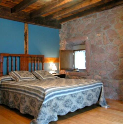 a bedroom with a large bed in a stone wall at Casa rural Ballenea in Errazu