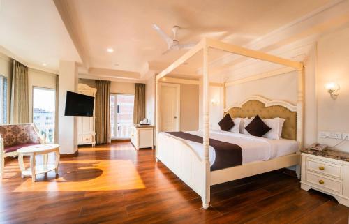 a bedroom with a canopy bed and a chair at Hotel Magenta-City Center Bani Park Jaipur in Jaipur