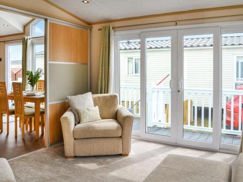 a living room with a chair and a sliding glass door at Lavender Lodge in Patrington
