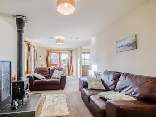 a living room with a leather couch and a fireplace at The Barn in Kilmory