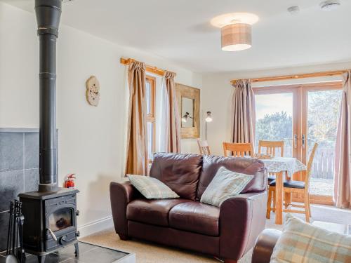 a living room with a leather couch and a wood stove at The Barn in Kilmory