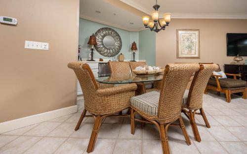 a dining room with a glass table and wicker chairs at Phoenix on the Bay 1324 in Orange Beach