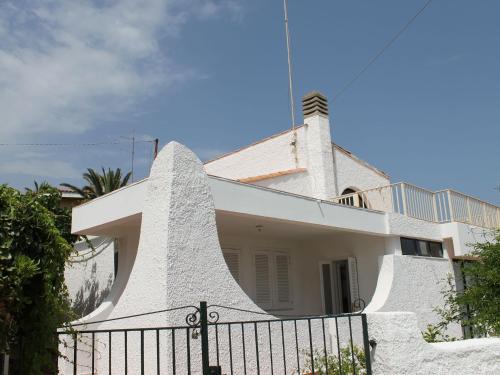 a white house with a fence in front of it at Belvilla by OYO Villa Eirene in Fontane Bianche