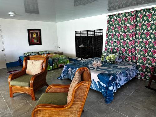 a room with two beds and two chairs at Eli Beach House in Vaiorea