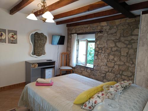 a bedroom with a bed and a stone wall at El Caserio de Esther in Beranga