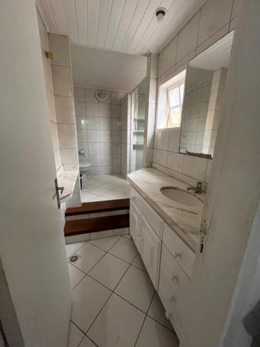 a white bathroom with a sink and a shower at Quarto em casa próx a rua das pedras in Búzios
