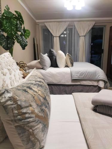 a bedroom with two beds with pillows and a couch at Magalies B&B SPITSKOP in Bloemfontein