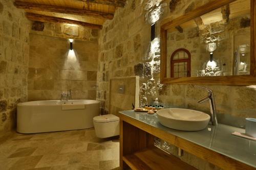 a bathroom with a tub and a toilet and a sink at Acropolis Cave Suite in Urgup