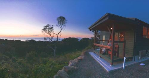 a person sitting on a bench in a tiny house at 屋久島 四季の宿 in Yakushima