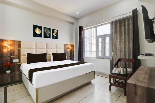 a bedroom with a large white bed and a window at Super Hotel O Gold Inn in Rohtak