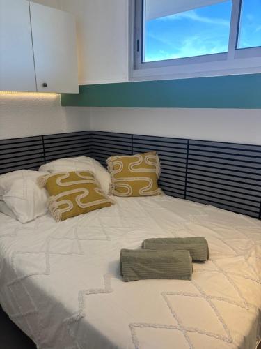 a large white bed with pillows and a window at Sunset in Cap d'Agde