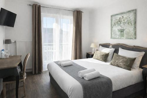 a bedroom with a bed with a desk and a window at Logis Hôtel Blue Garden in Grandvillers