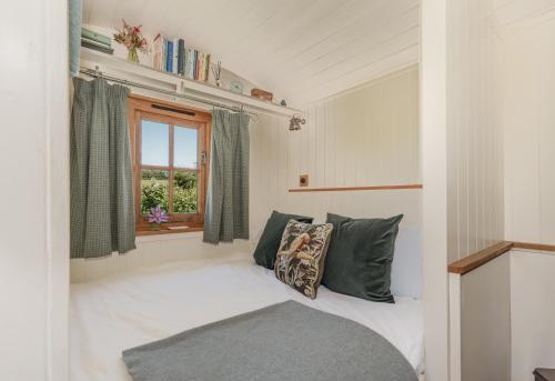 a room with a bed with pillows and a window at Hurdlemakers Hut in Dorchester