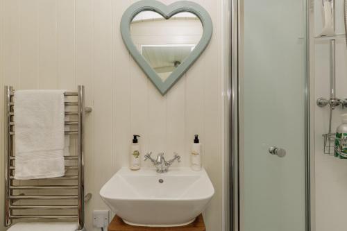 a bathroom with a sink and a heart mirror at Hurdlemakers Hut in Dorchester