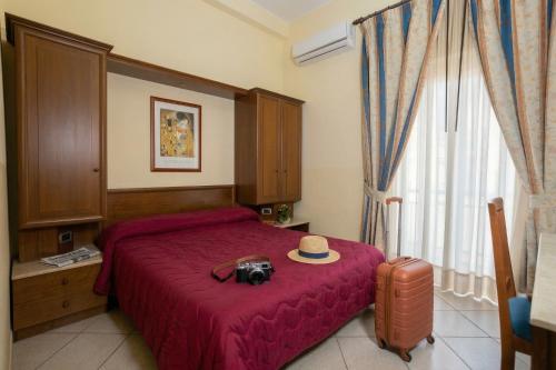 a bedroom with a camera and a hat on a bed at Hotel Gangi in Piazza Armerina