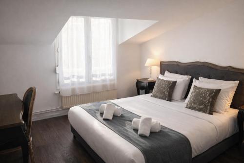 a bedroom with a large bed with two towels on it at Logis Hôtel Blue Garden in Grandvillers