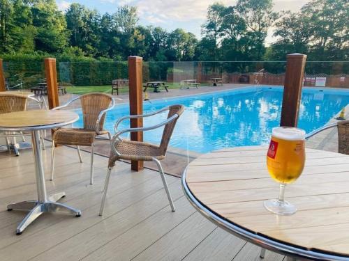a glass of beer sitting on a table next to a pool at Cabin 246 Riverside, Glan Gwna in Caeathro