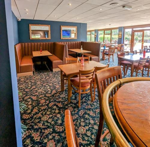 a restaurant with wooden tables and chairs and tables and chairs at Cabin 246 Riverside, Glan Gwna in Caeathro