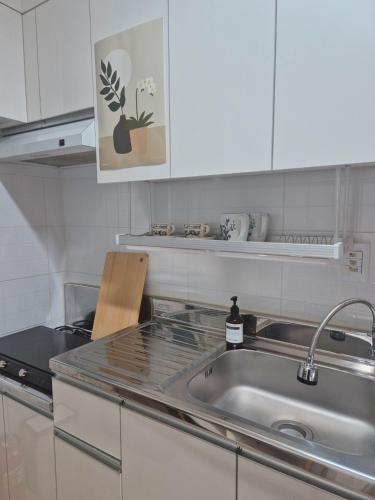 a kitchen with a stainless steel sink and white cabinets at Daon 101 in Seoul