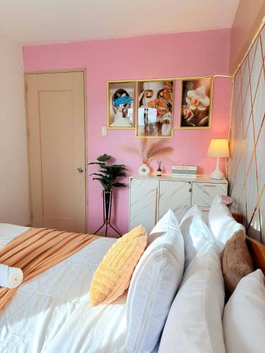 a bedroom with a white bed and a pink wall at Relaxing 2BR at Camella Northpoint with balcony pool view 3rd floor in Davao City