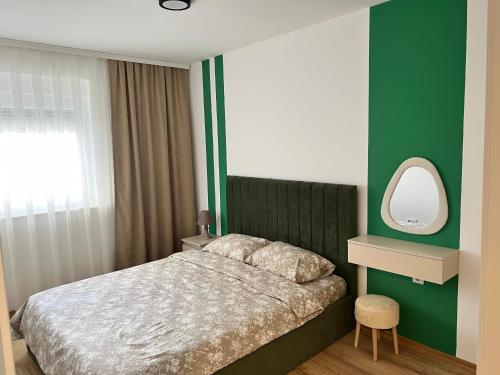 a bedroom with a bed with a mirror and a green wall at Union Apartment in Ferizaj