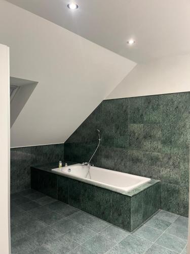 a white bath tub in a room with green tiles at Dom pod lesom v Borinke in Stupava