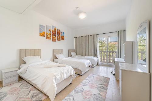 a bedroom with two beds and a television in it at Specious 2BR VILLA WITH MAIDROOM AND HUGE GARDEN IN JVT DUBAI in Dubai