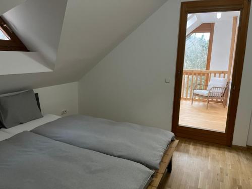 a bedroom with a bed and a balcony with a chair at Dom pod lesom v Borinke in Stupava