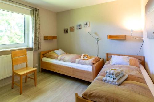 a bedroom with two beds and a chair and a window at Hus-Pellworm-1-Ferienwohnung-Meerestraum in Pellworm