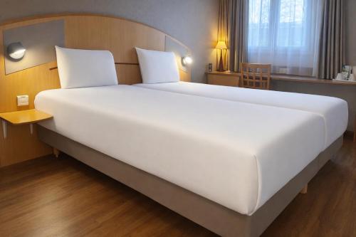 a large white bed in a hotel room at Kyriad Hotel Montpellier Centre Antigone in Montpellier