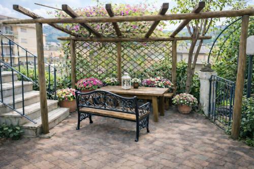 a bench sitting under a pergola with a table and flowers at Casa Lapè in Levanto