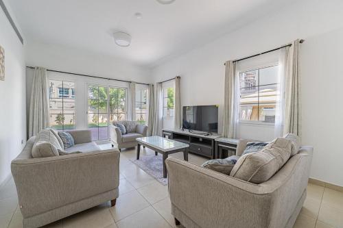 a living room with two couches and a tv at Specious 2BR VILLA WITH MAIDROOM AND HUGE GARDEN IN JVT DUBAI in Dubai