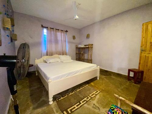 a bedroom with a white bed and a window at HIGSAM apartment in Ukunda