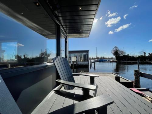 a wooden deck with a chair sitting on a boat at Poellodge, Luxe houseboot met zonnig terras in Aalsmeer