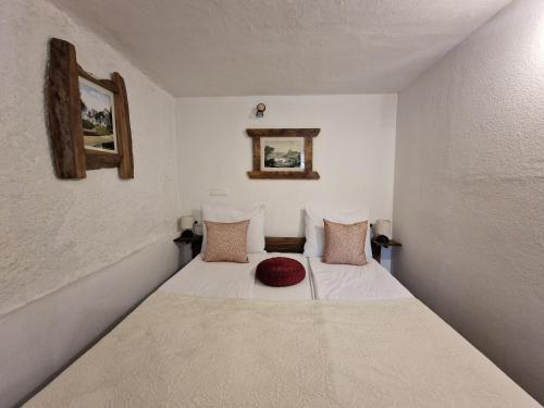 a small bedroom with a bed with a red hat on it at Slovenian House Vida in Bled