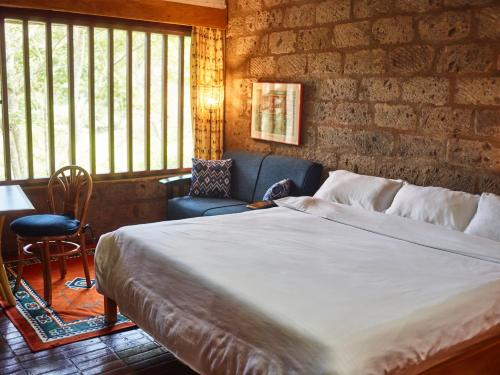 a bedroom with a bed and a chair and windows at Villa Rock Stop Falls Gigiri in Nairobi