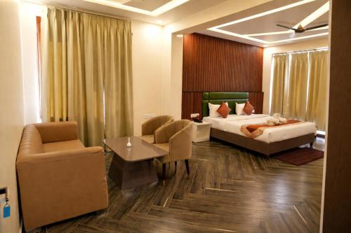 a hotel room with a bed and a couch and chair at Tulsi Resort in Gorakhpur