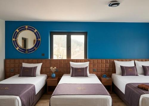 two beds in a room with blue walls and a mirror at Hôtel De La Promenade in Chevigney