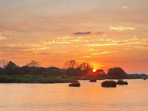 a sunset over a river with islands in the water at Tena Don Det Sunset Guest House in Don Det