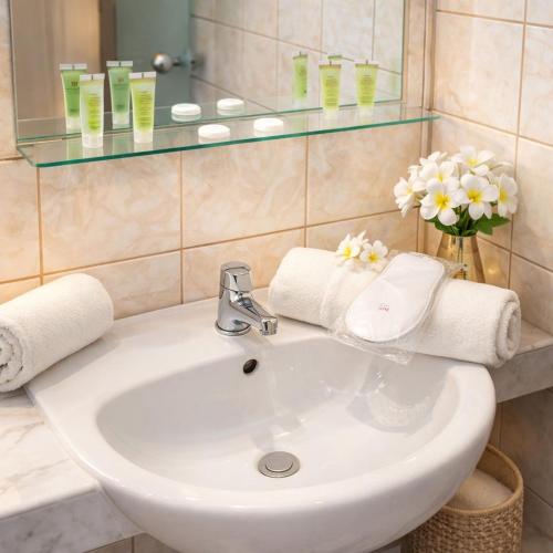 ein Badezimmer mit Waschbecken, Spiegel und Blumen in der Unterkunft Markos Studios Potos Thassos in Potos