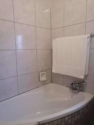 a white tiled bathroom with a bath tub and a towel at Panorama home 19 in Graskop