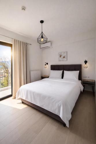 a bedroom with a large white bed and a window at White Rocks Meteora in Kalabaka