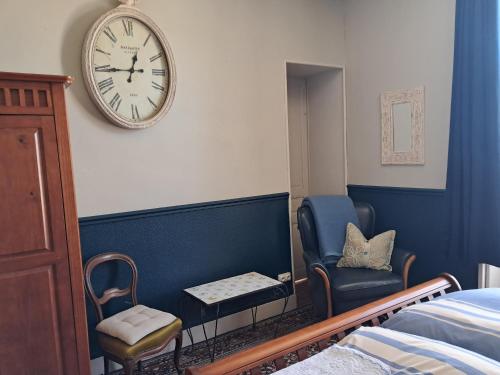 a bedroom with a chair and a clock on the wall at Thunder Roadhouse in La Mothe-Saint-Héray